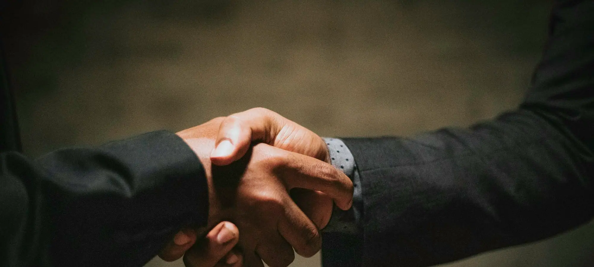 Two business partners shaking hands over a table