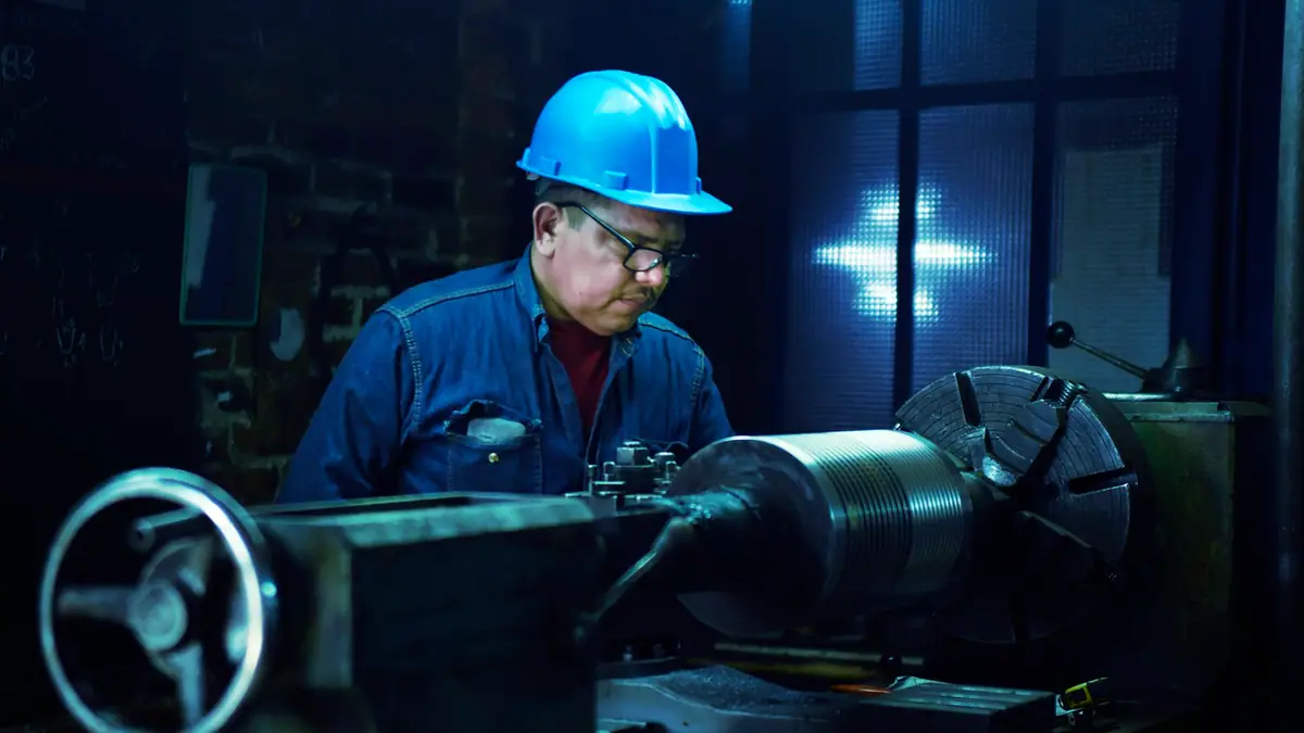 Technician in a hard hat servicing industrial machinery