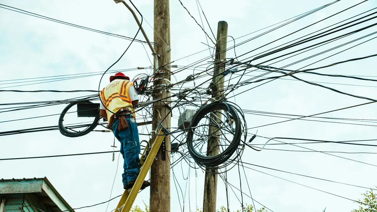 Lineman in a hard hat working on a utility pole