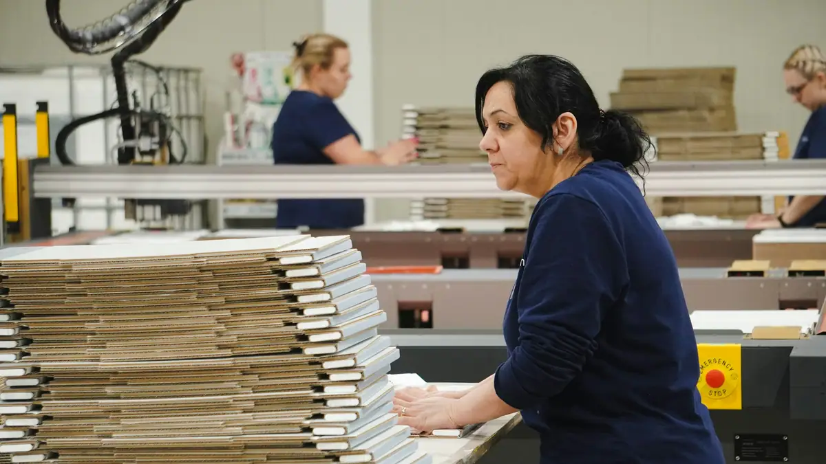 Worker stacking cardboard packaging on a production line