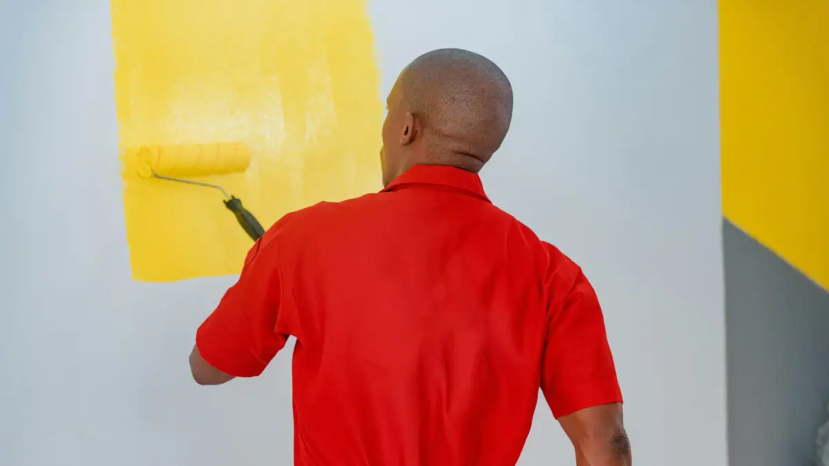 Commercial painter rolling yellow paint onto a wall