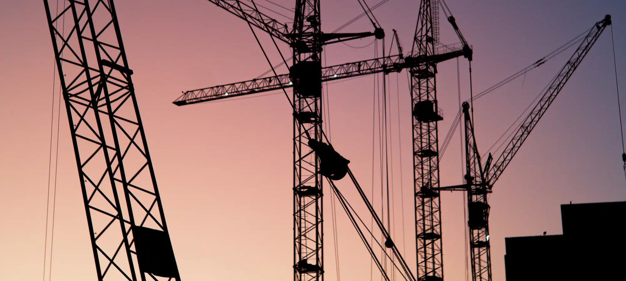 Tower cranes over a construction site at dusk