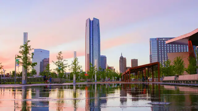 Downtown Oklahoma City towers reflected in water at sunset