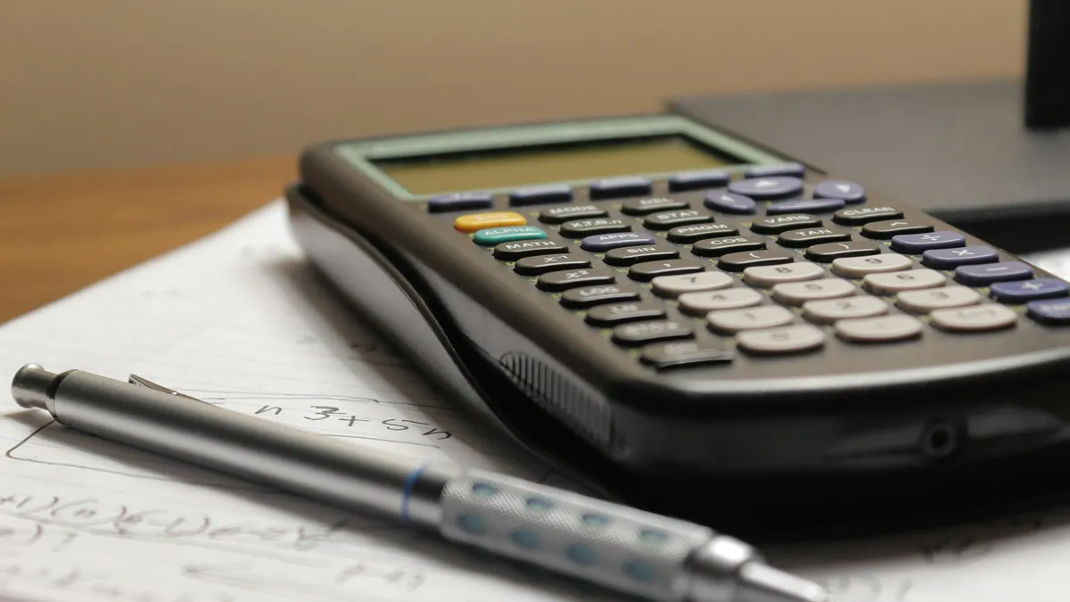 Calculator and pen on a page of handwritten figures