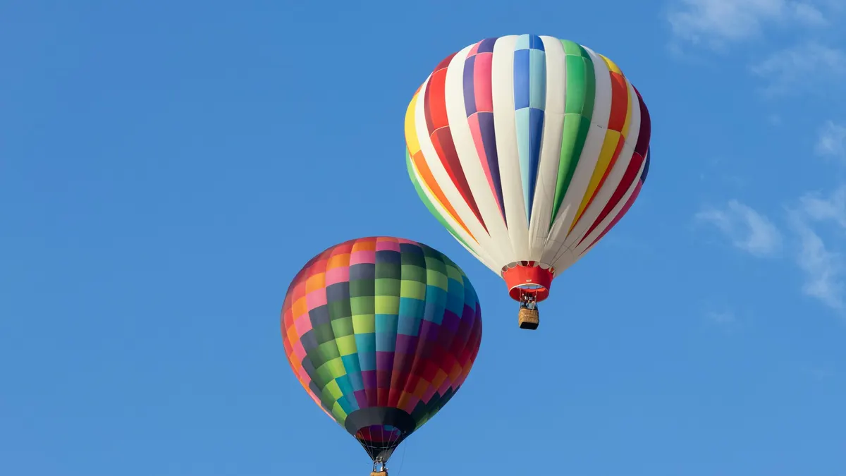 Two colorful hot air balloons in a blue sky
