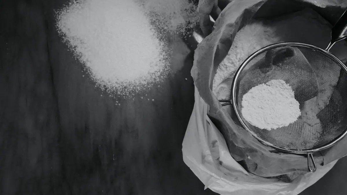 Hands sifting powder through a sieve