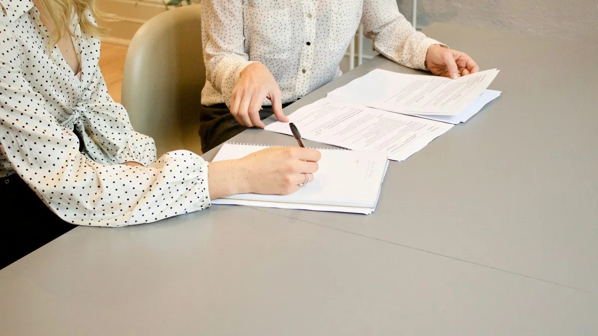 Two people reviewing and signing documents at a table