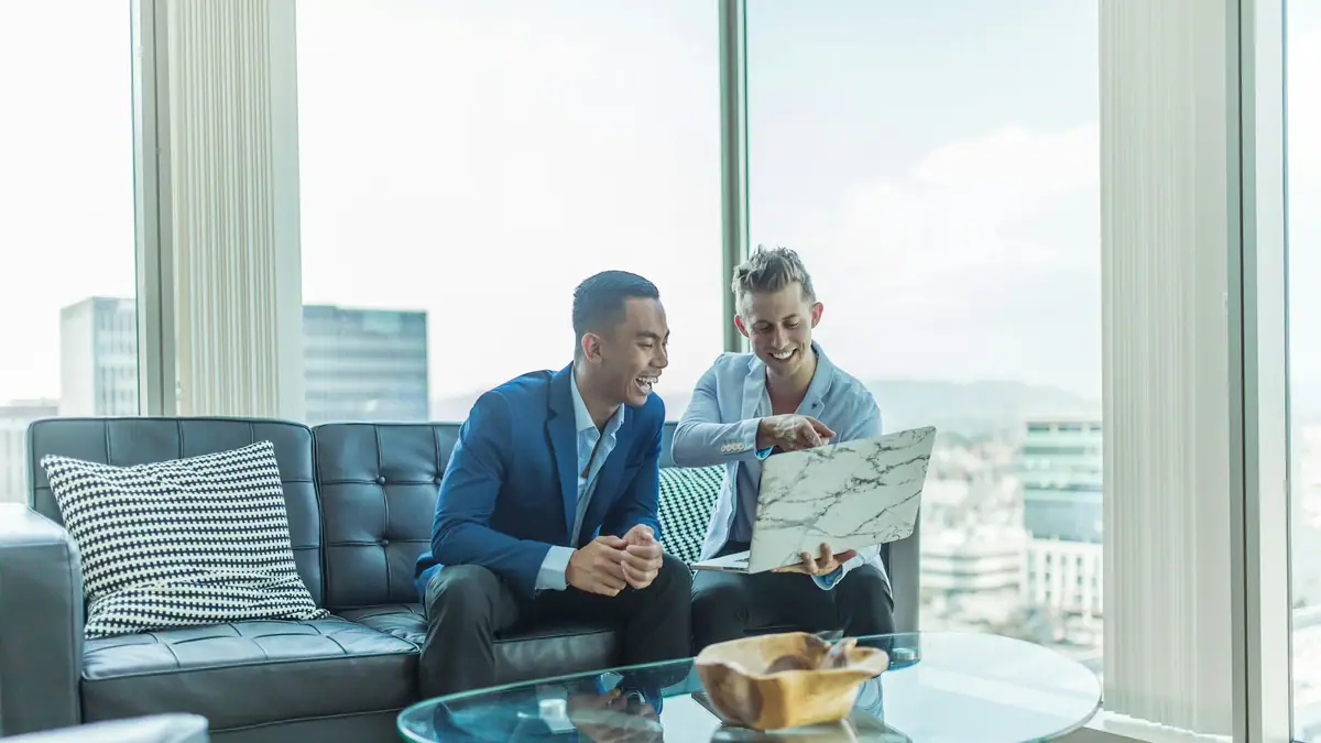 Two advisors in suits reviewing documents on a sofa