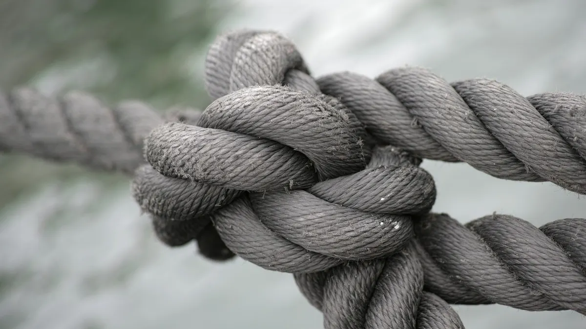 Close-up of a tight knot joining two grey ropes