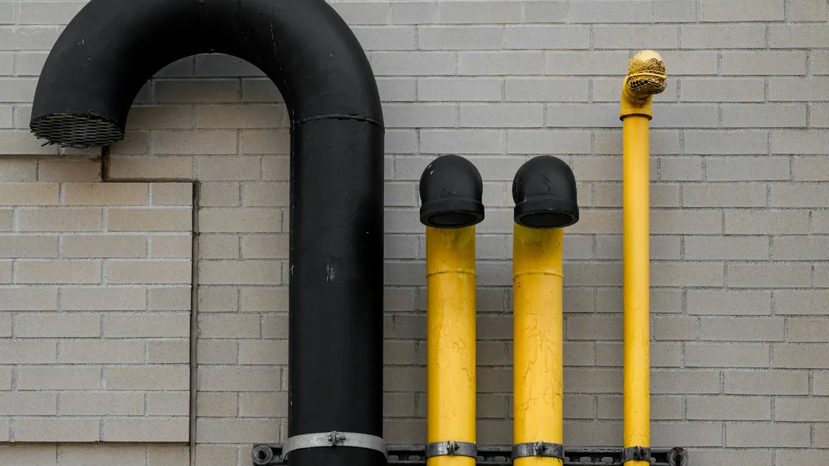 Black and yellow pipes running along a brick wall