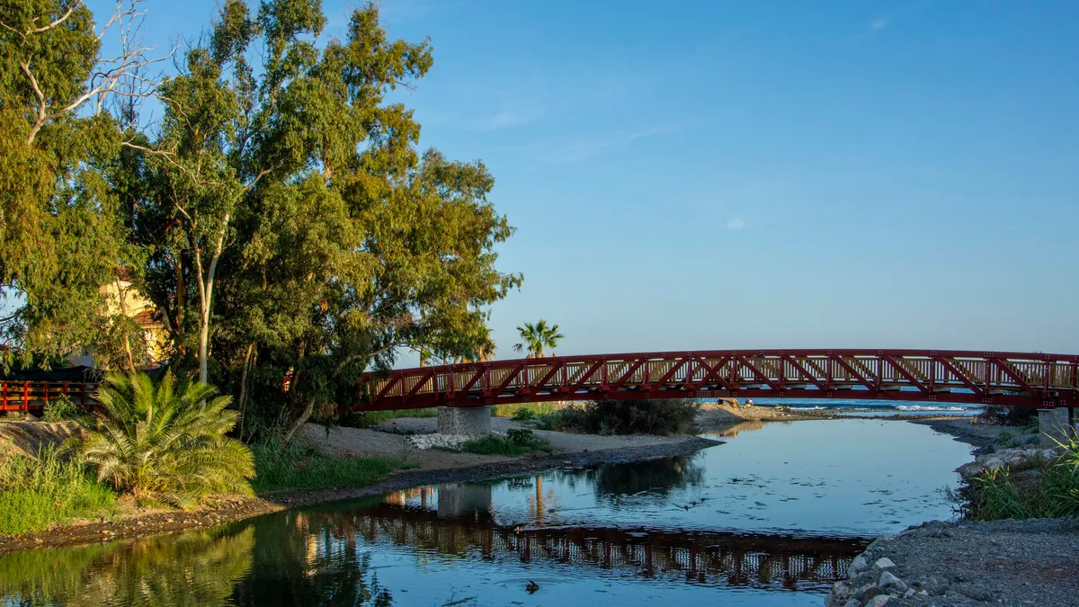 Red pedestrian bridge over a calm river at dusk