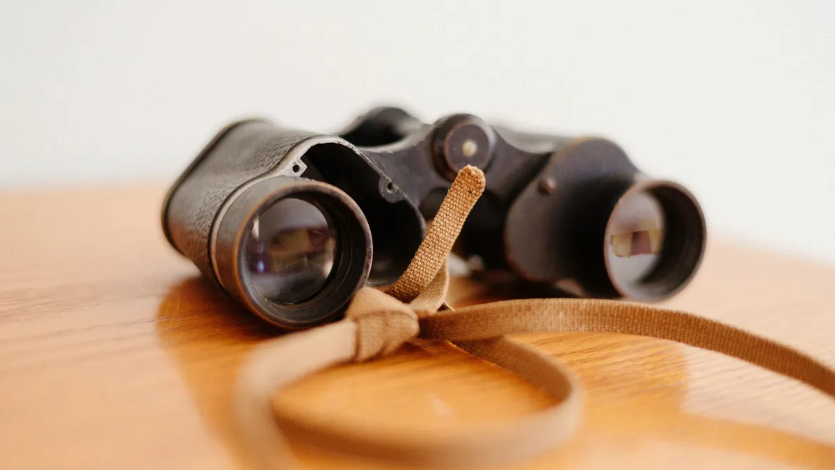 Vintage binoculars with a leather strap on a wooden table