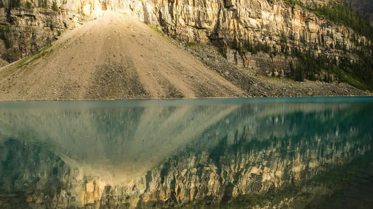 Mountain face mirrored in a still green lake