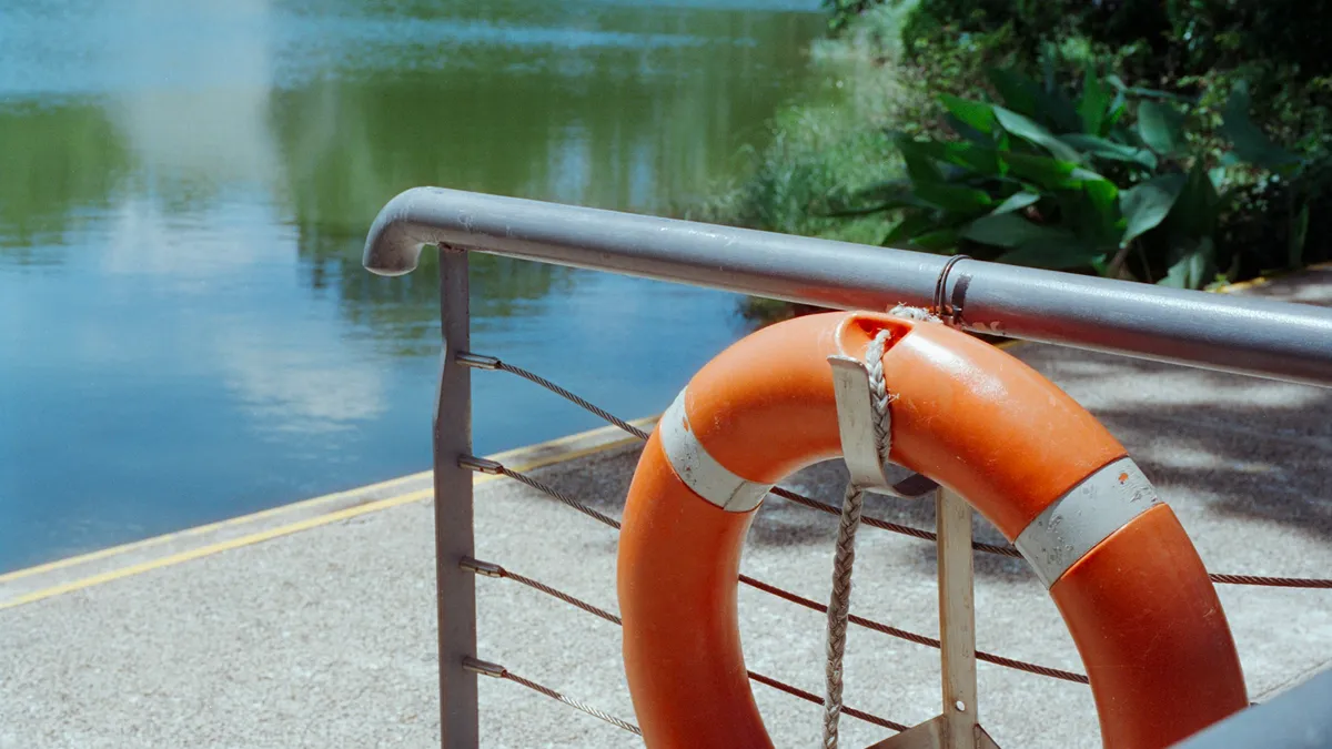 Orange life ring hanging on a railing by the water