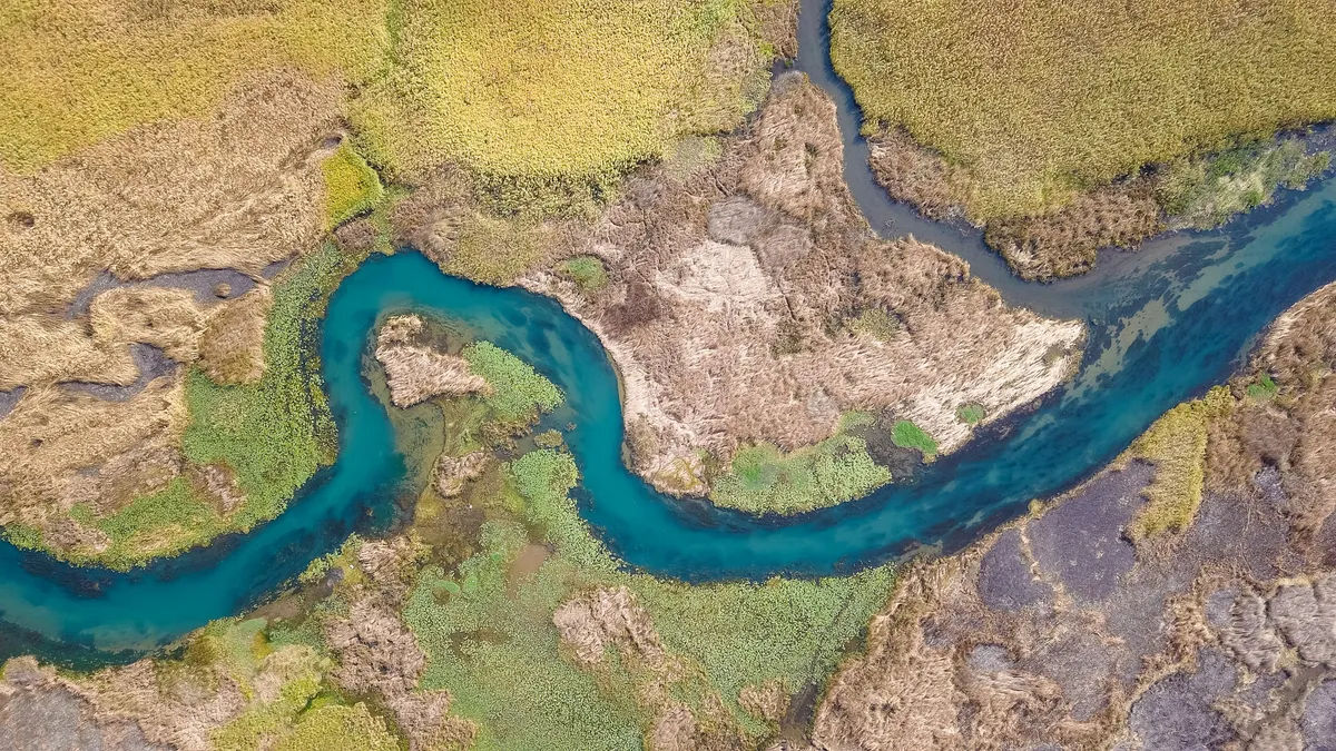 Aerial view of a blue river winding through marshland