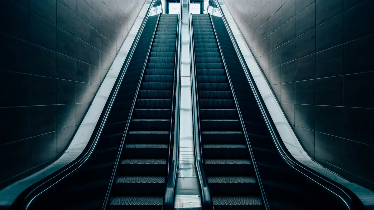 Twin escalators rising through a dark tiled passage