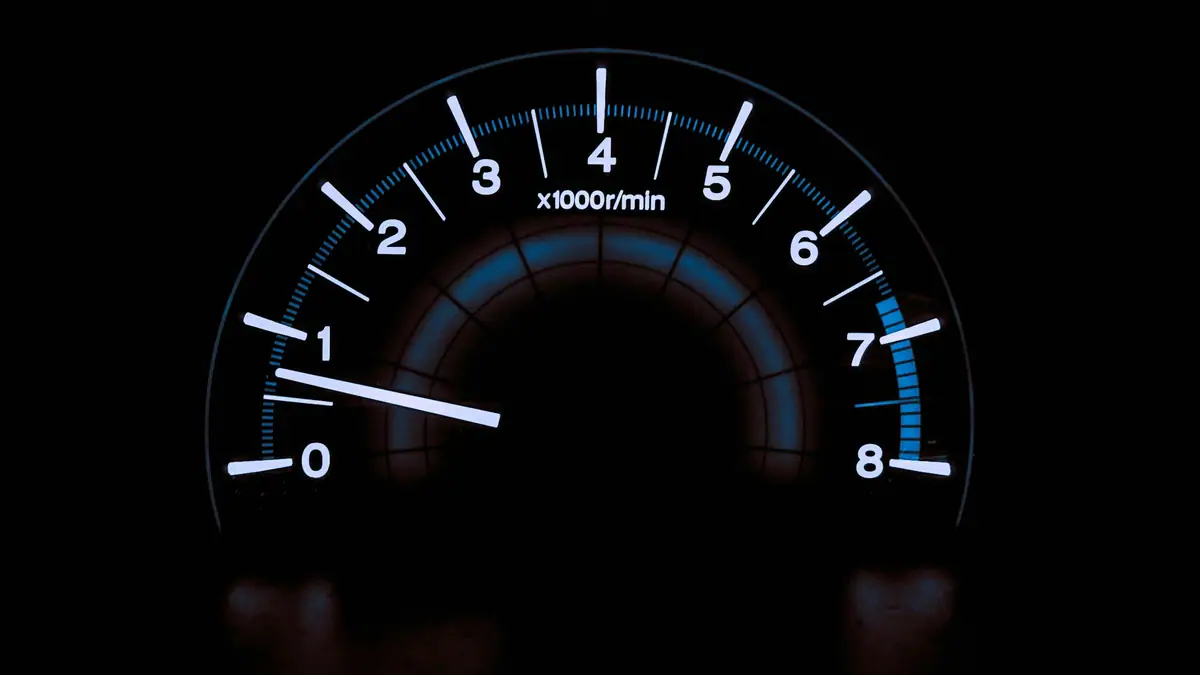 Illuminated tachometer gauge on a dark dashboard