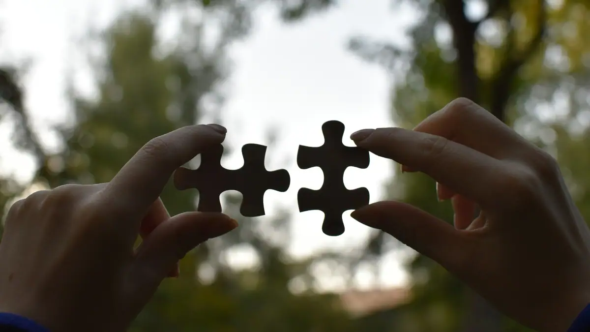 Two hands fitting puzzle pieces together
