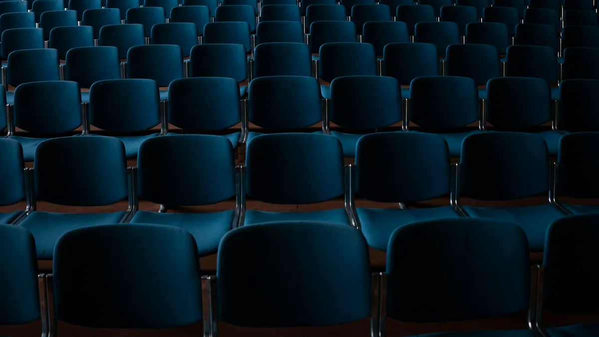Rows of empty blue seats in a dim auditorium