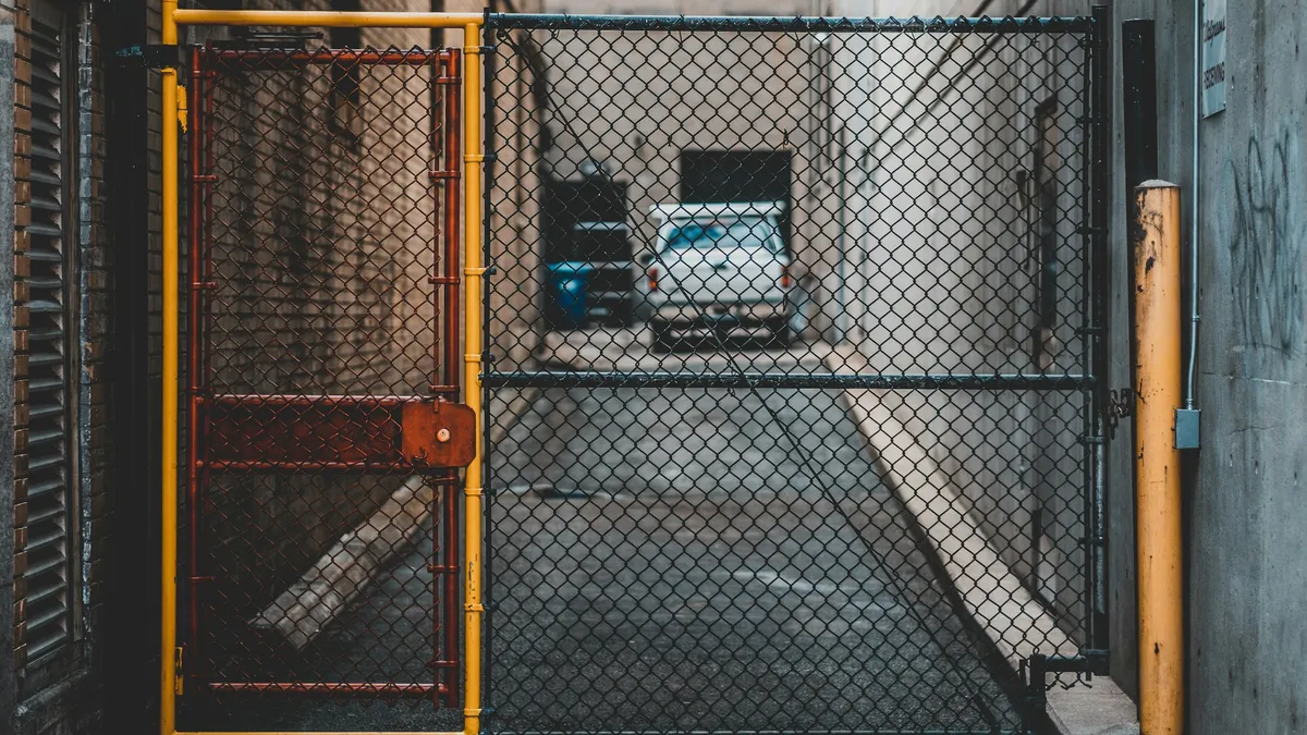 Yellow-framed chain-link gate closing off an alley