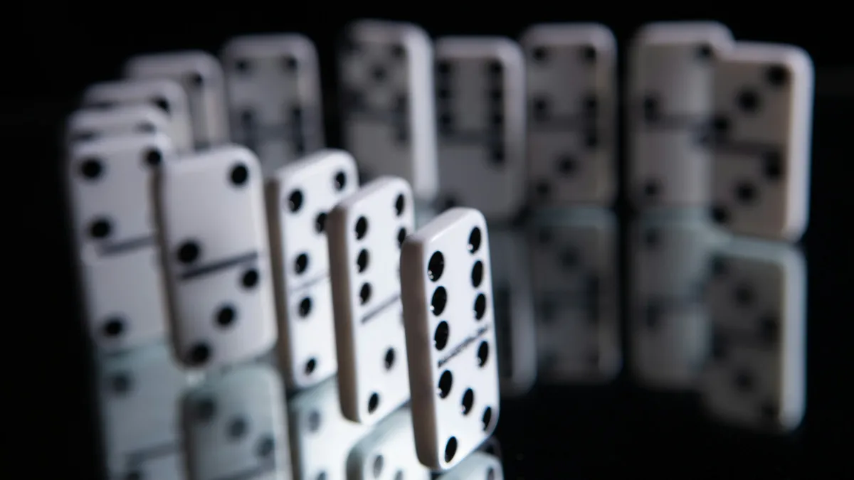 White dominoes standing in a curved line on a reflective surface