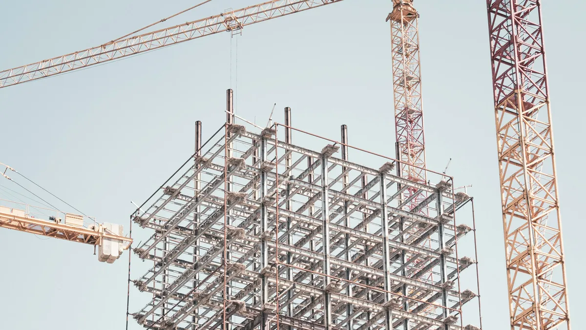 Steel building frame rising between tower cranes