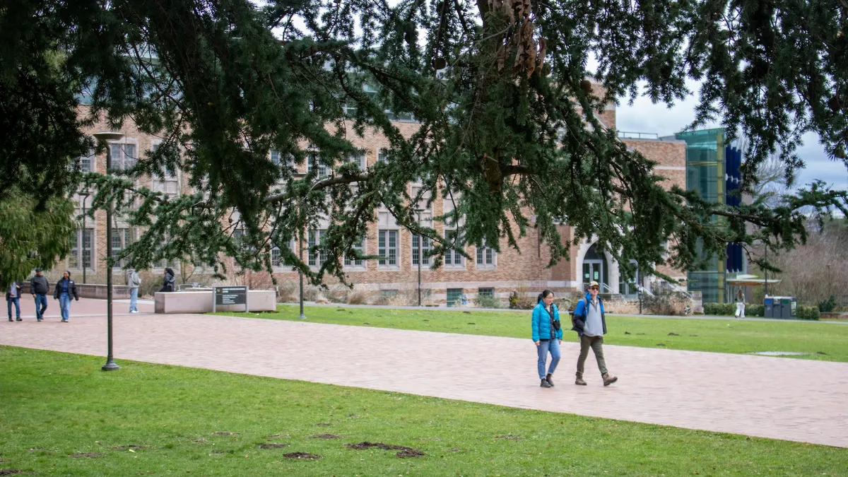 Students walking across a university campus lawn