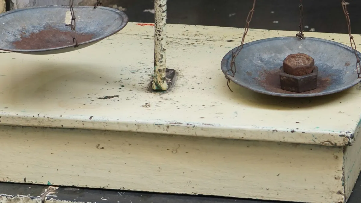 Weathered balance scale with a weight on one pan