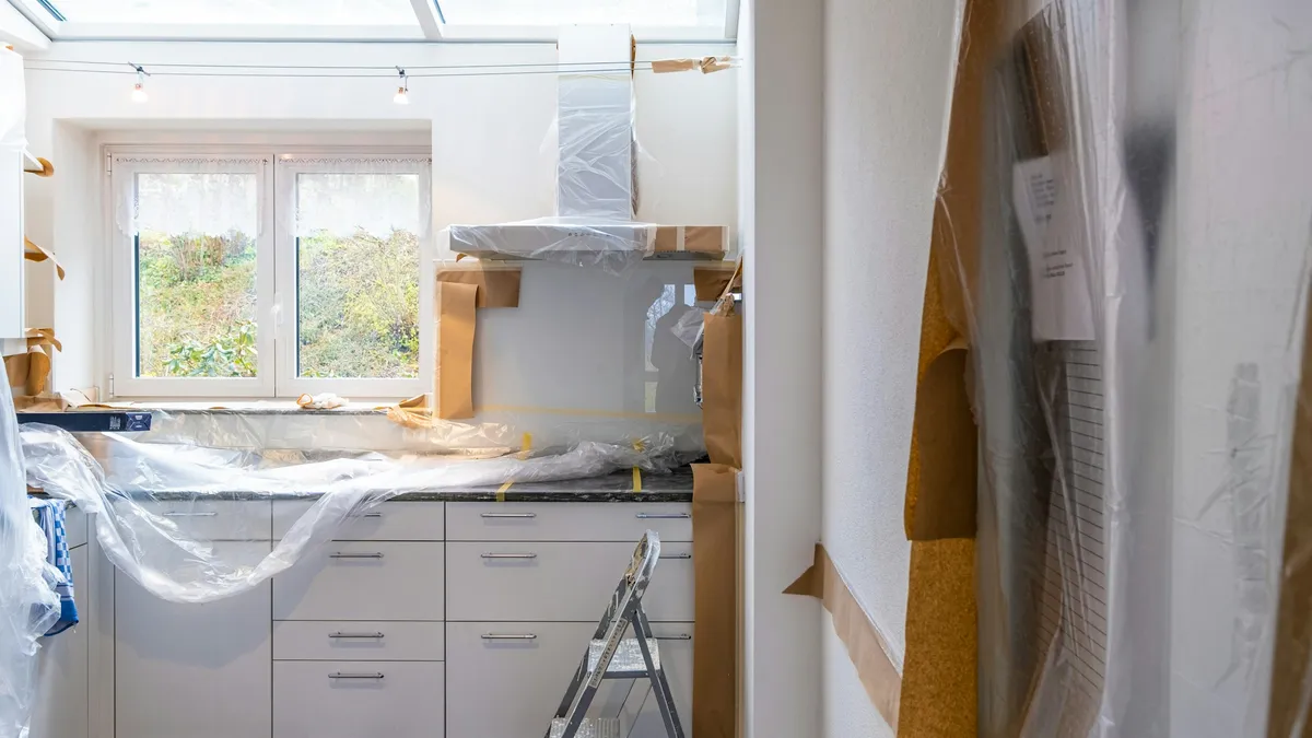 Kitchen mid-renovation with cabinets wrapped in plastic