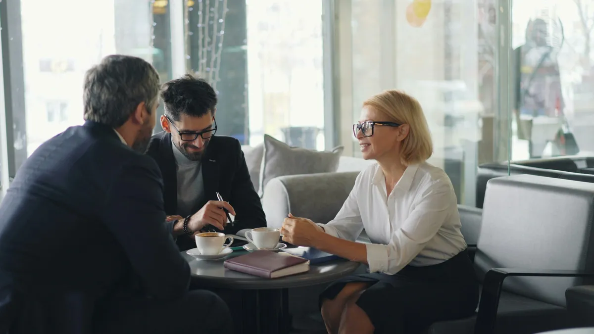 Advisor meeting with two clients over coffee