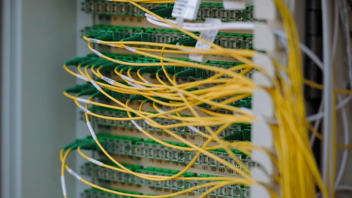 Yellow fiber cables patched into a network panel