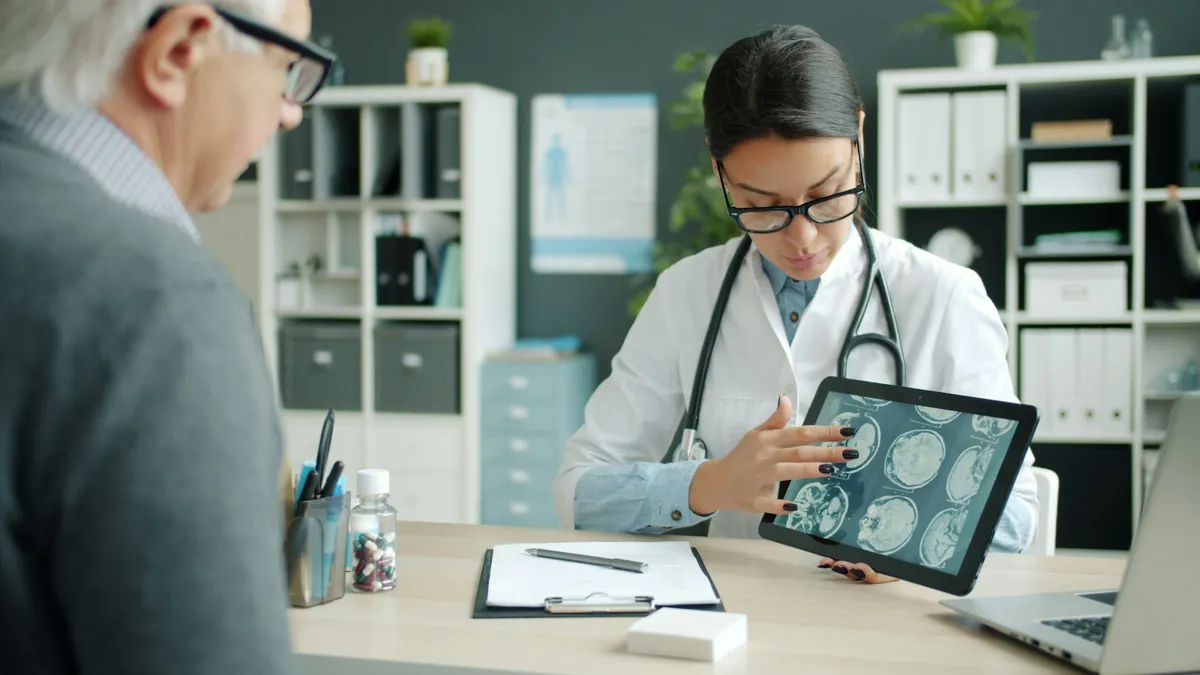 Doctor reviewing brain scans on a tablet with a patient