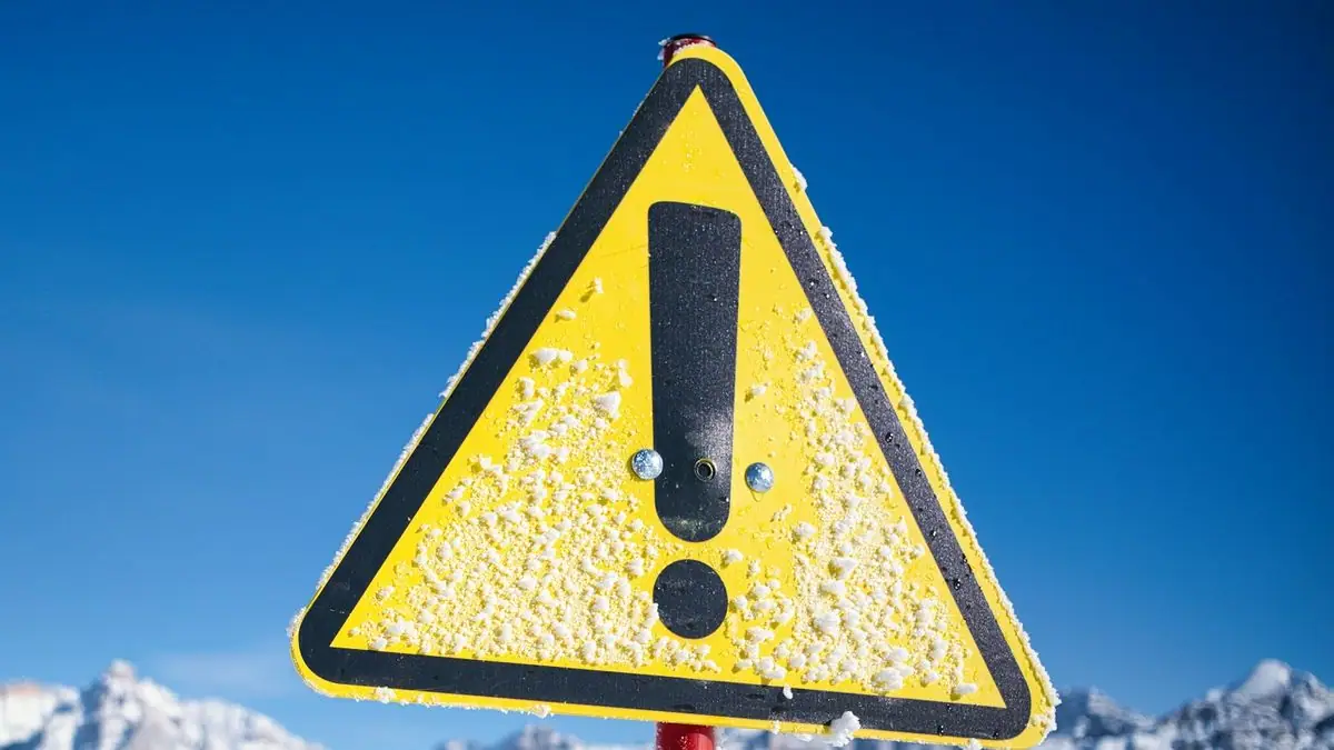 Yellow triangular warning sign with an exclamation mark against a blue sky