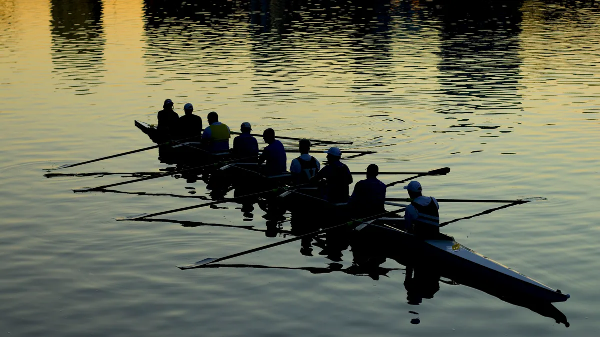 Rowing crew silhouetted on calm water at dusk