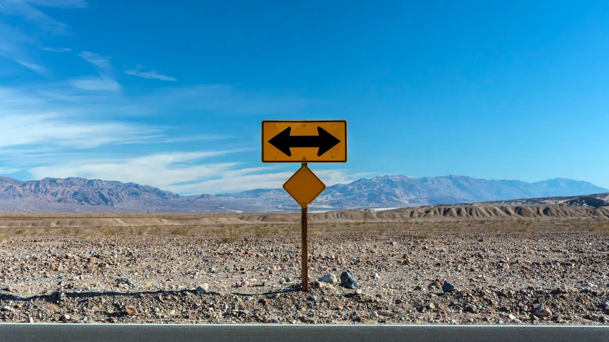 Road sign with arrows pointing in opposite directions