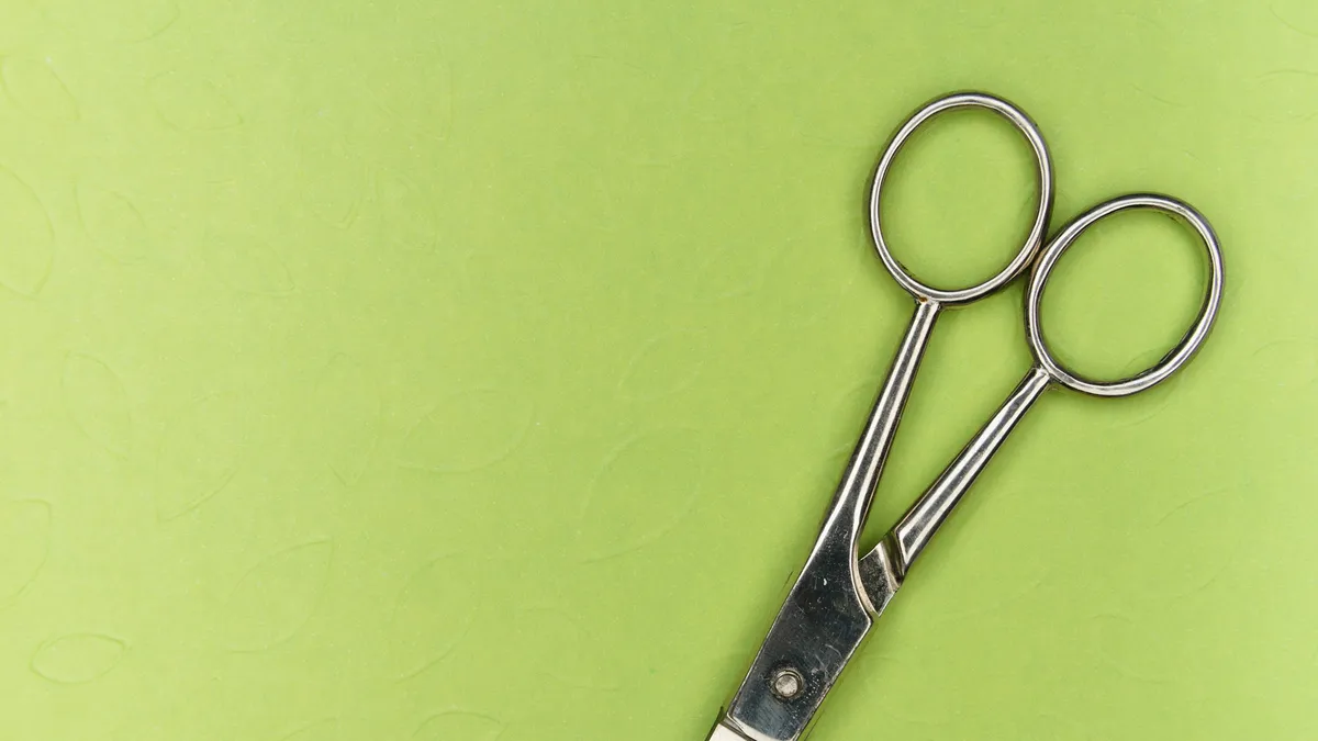 Steel scissors on a bright green surface