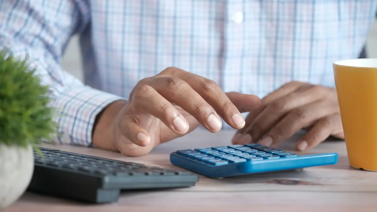 Hands working a calculator at a desk