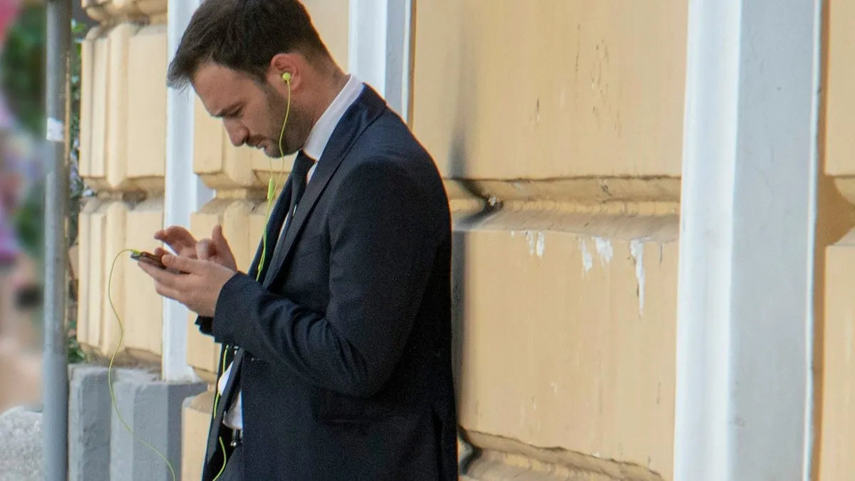 Man in a suit checking his phone outside a building