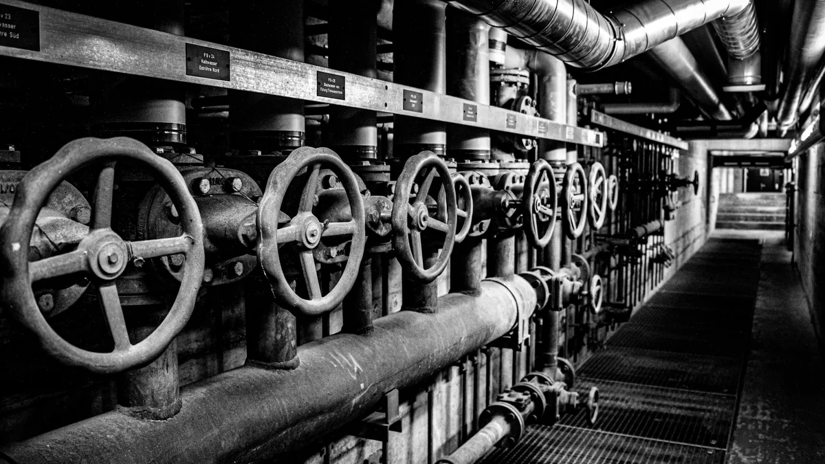 Rows of valve wheels along an industrial pipe corridor