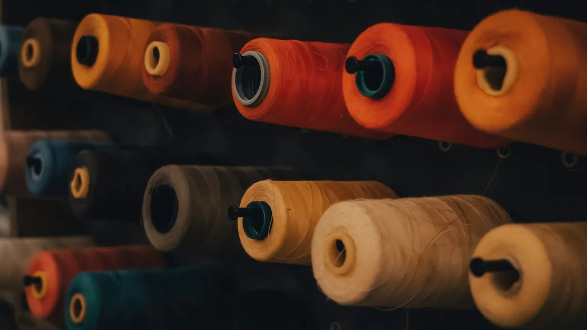 Rows of thread spools in many colors on a wall rack