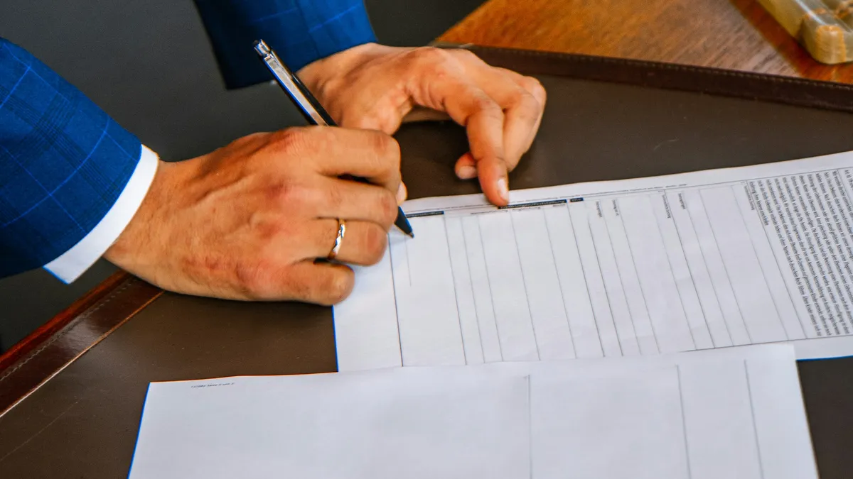 Person filling out and signing a printed form