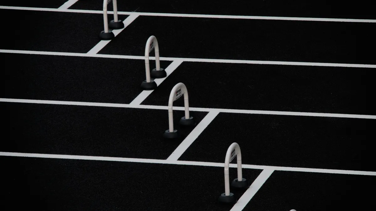 Evenly spaced hurdles across a black running track