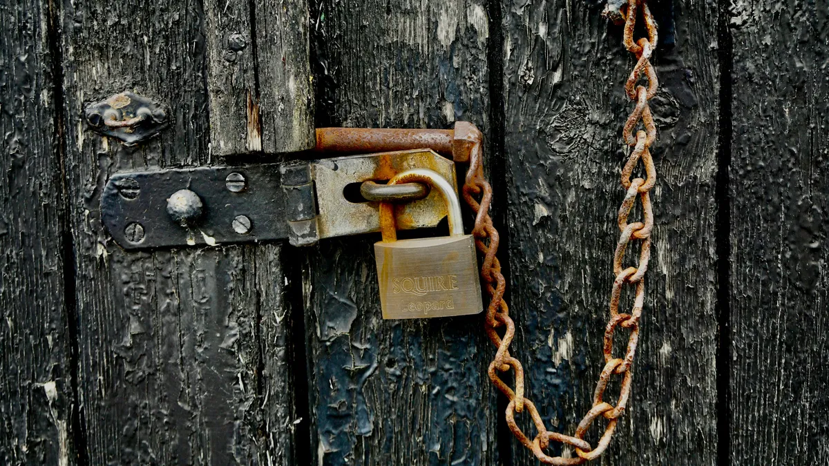 Brass padlock and chain on a weathered black door