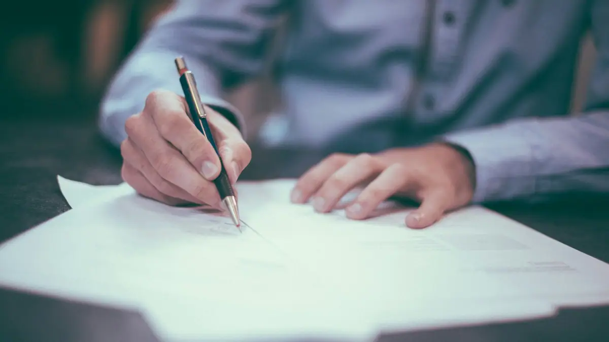 Hand signing a document with a pen