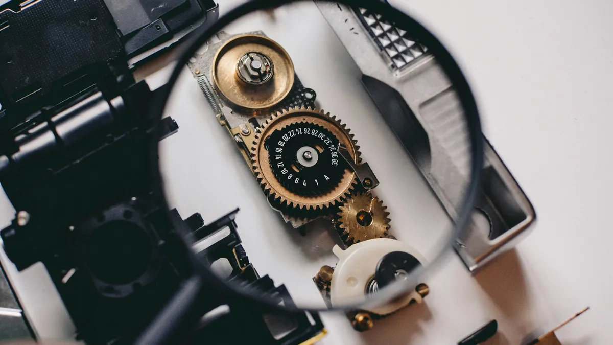 Magnifying glass held over the gears of a mechanism