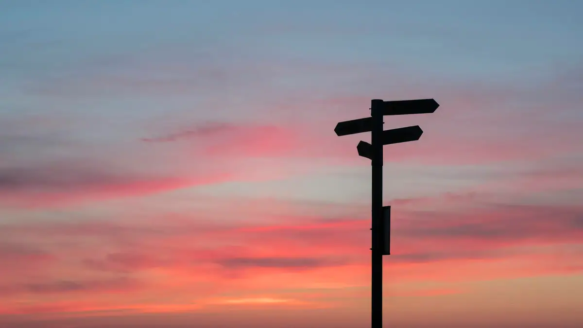 Signpost silhouetted against a sunset sky