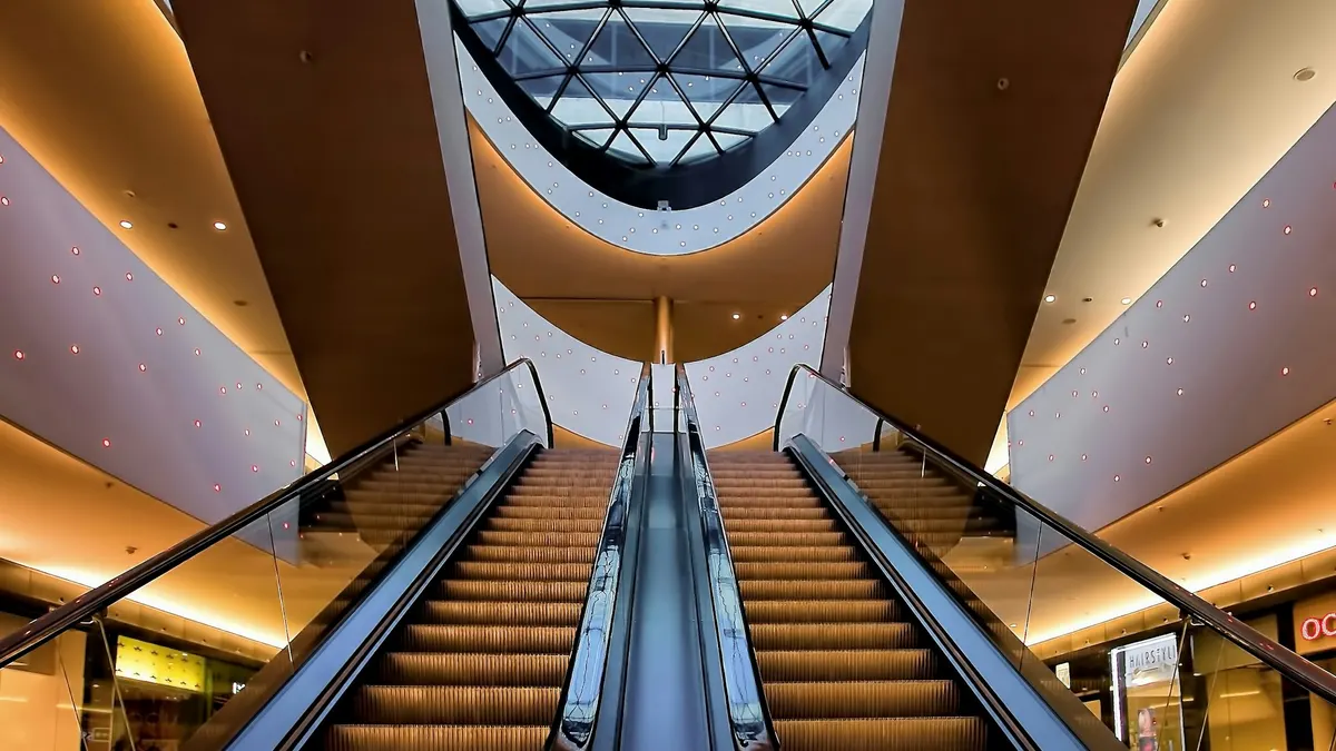 Two side-by-side escalators under warm ceiling lights