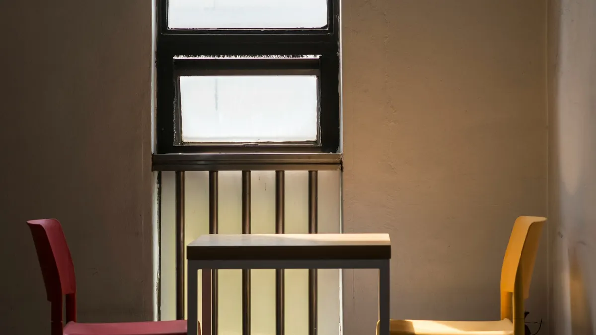 Red and yellow chairs at a small table by a sunlit window