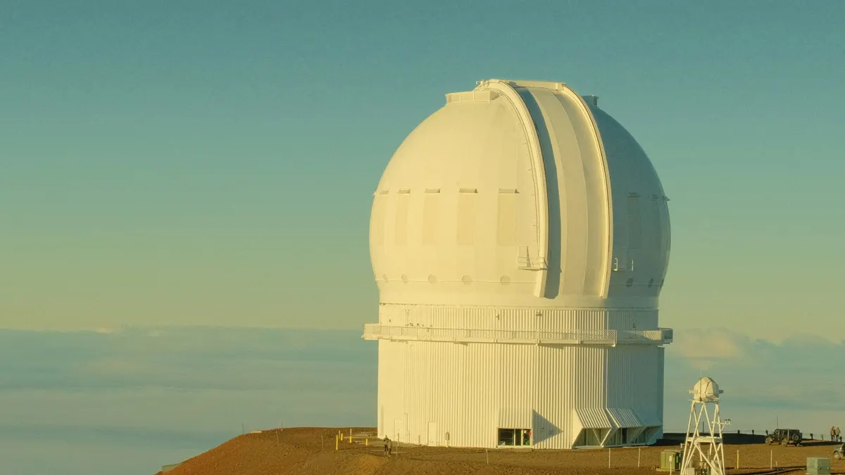 White observatory dome on a mountain peak above the clouds
