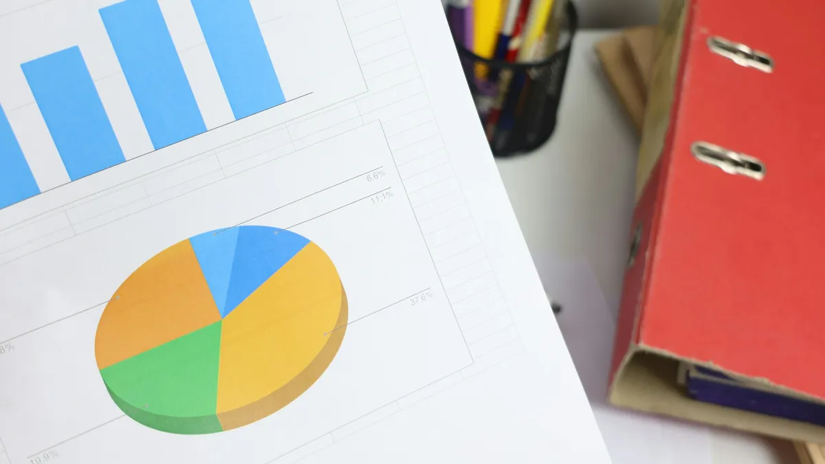 Printed bar and pie charts beside a red binder